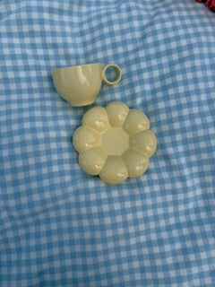 Tasse jaune pastel minimaliste avec sous tasse fleur effet bubble posées sur une nappe vichy bleu clair, vue de dessus dans une ambiance esthétique et cosy 